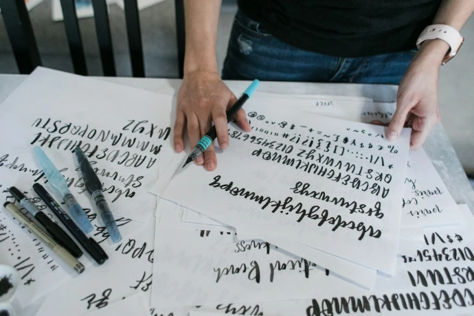 person holding pen writing on white paper